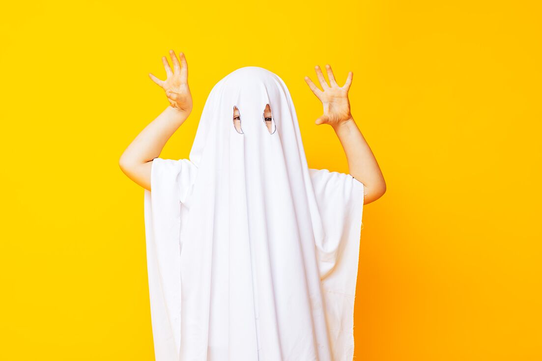 Kleines Kind trägt niedliche Halloween-Geister-Kostüm auf gelbem Hintergrund